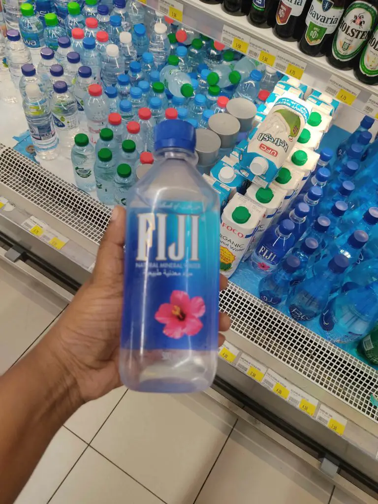 A person holding a FIJI bottled water in the supermarket